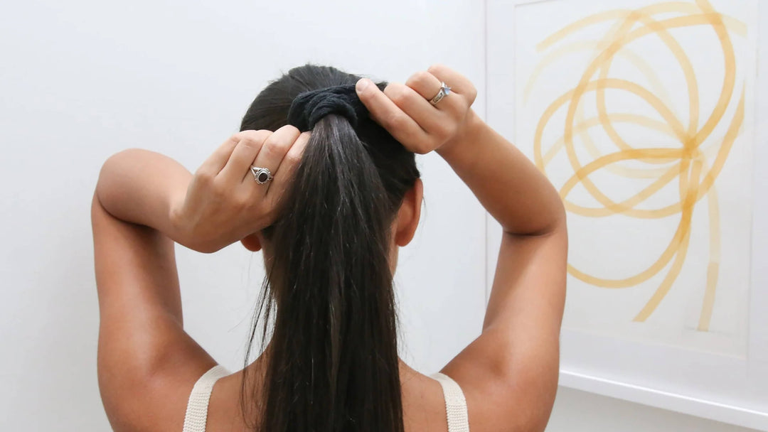 Woman gathering long black hair into a ponytail