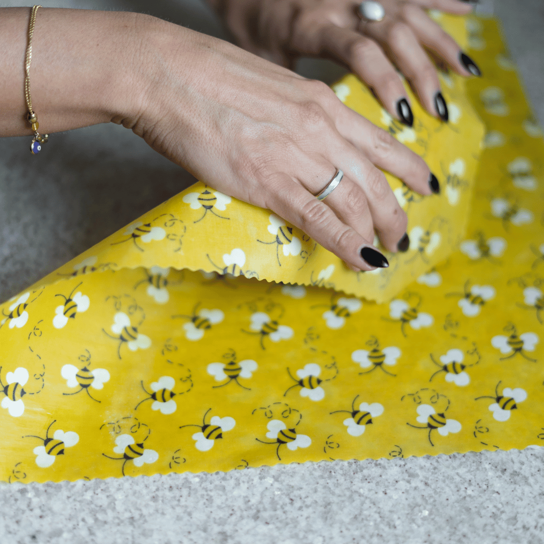Woman folding a beeswax wrap in yellow bee pattern