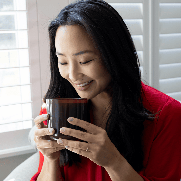 Asian woman smelling clean fragrance candle in brown glass jar